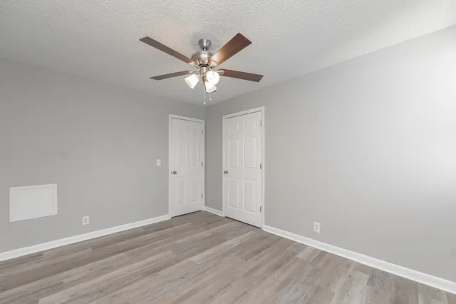 a view of a room with wooden floor and a ceiling fan