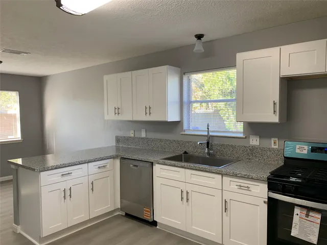 a kitchen with granite countertop white cabinets white appliances and a window