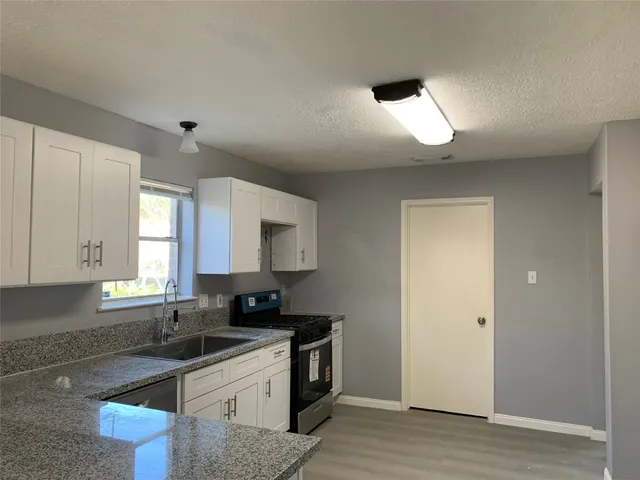 a kitchen with granite countertop a sink stainless steel appliances and cabinets
