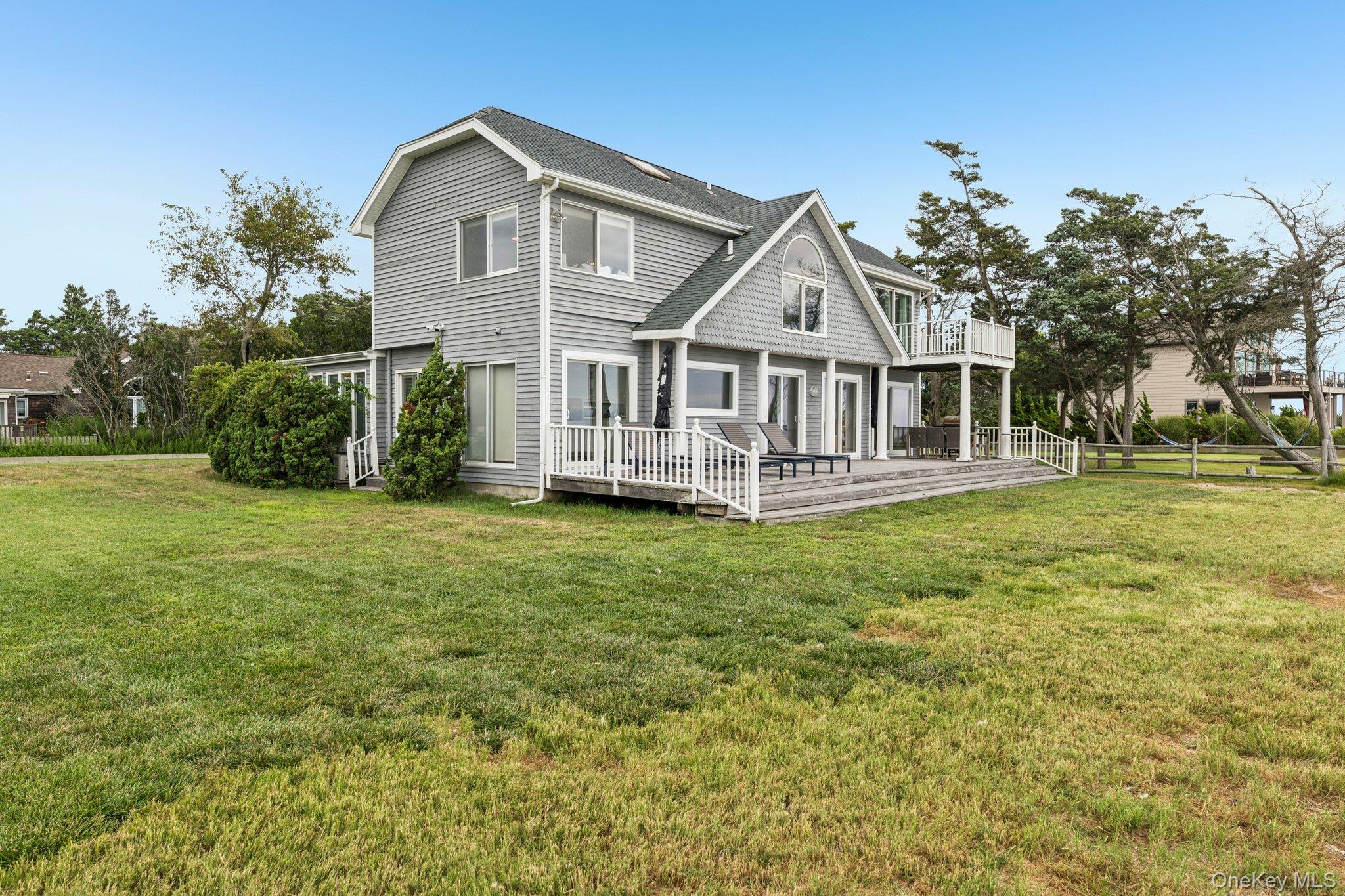 Back of property with a wooden deck and a shingled roof