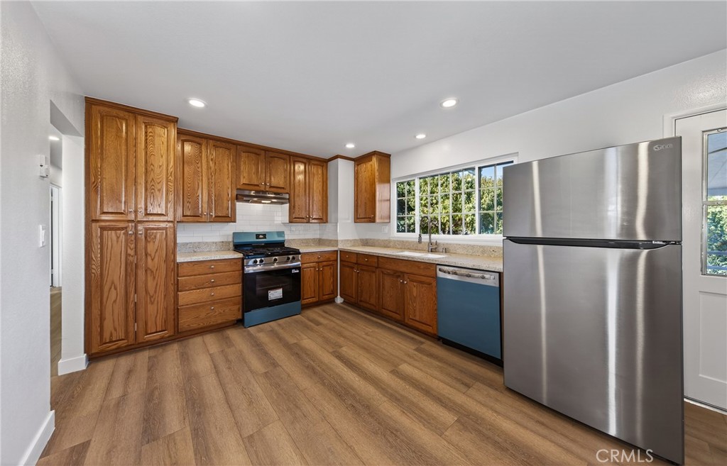 201 Primrose Avenue Redlands, CA 92373 - Photo 12 of 23 a kitchen with stainless steel appliances granite countertop a refrigerator a sink dishwasher a stove with large countertops and wooden floor