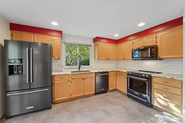 a kitchen with stainless steel appliances granite countertop a refrigerator stove and sink