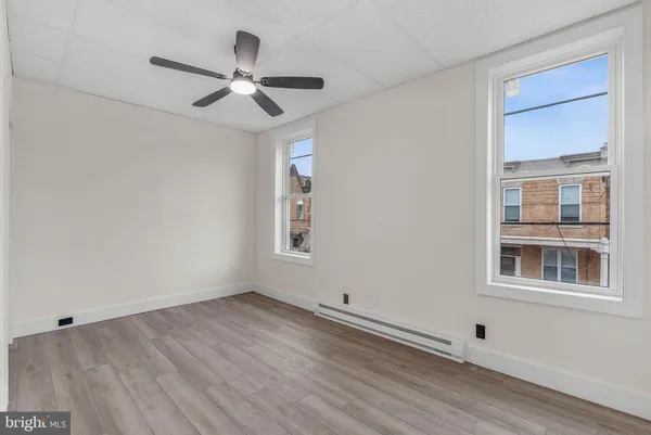 a view of empty room with wooden floor and fan