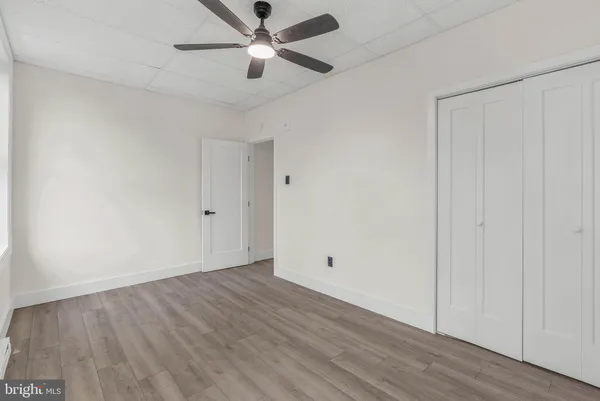 an empty room with wooden floor ceiling fan and windows