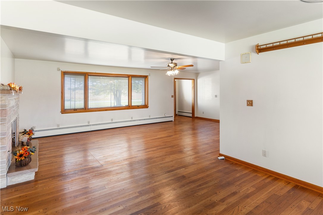 948 Carson Salt Springs Road Warren, OH 44481 - Photo 11 of 31 Unfurnished living room featuring hardwood / wood-style flooring, a baseboard radiator, and a brick fireplace