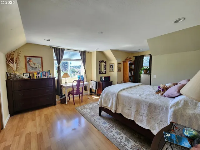 a spacious bedroom with a bed and wooden floor