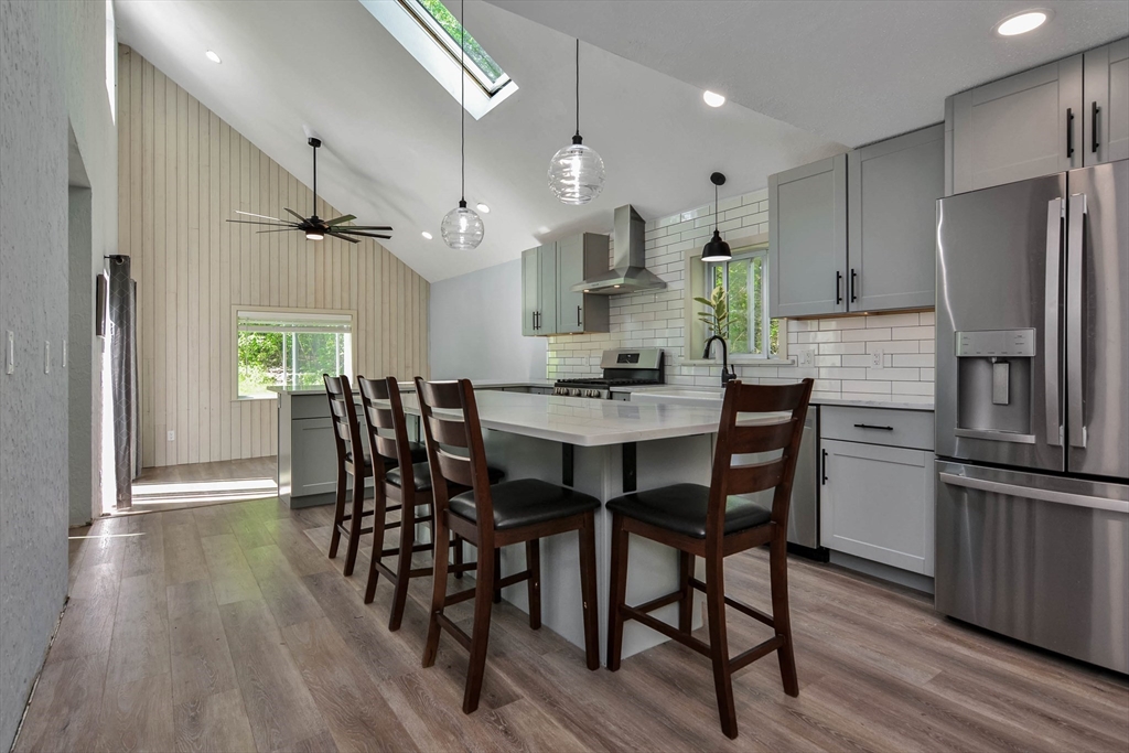 a dining room with stainless steel appliances kitchen island granite countertop furniture wooden floor and a kitchen view