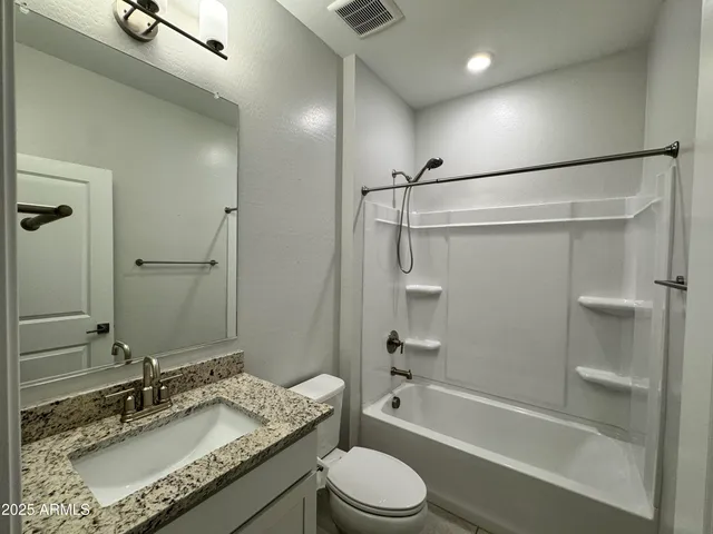 a bathroom with a granite countertop sink toilet and shower