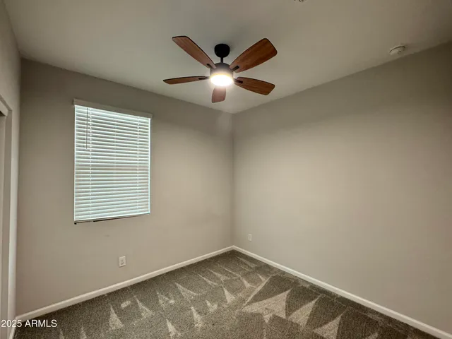a view of an empty room with window and ceiling fan
