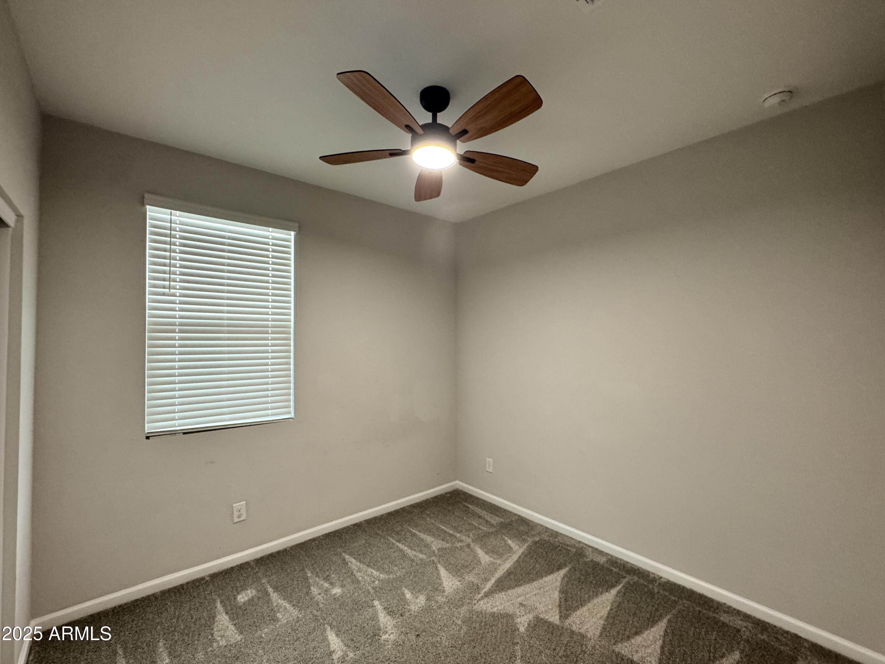 18228 West Daley Lane Surprise, AZ 85387 - Photo 5 of 18 a view of an empty room with window and ceiling fan