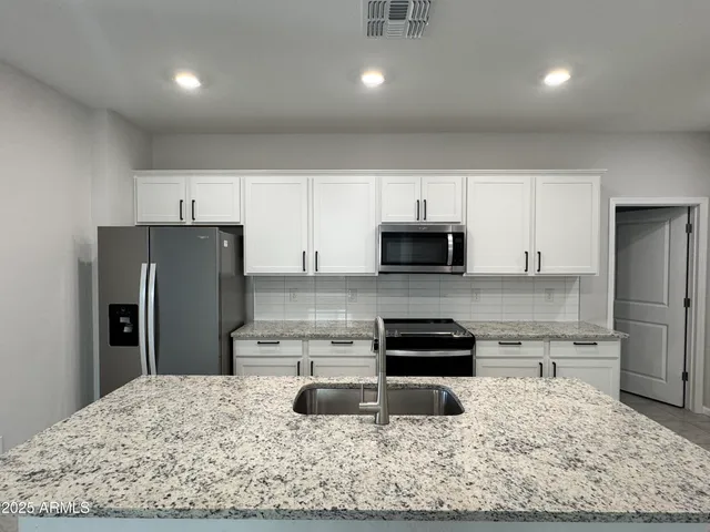 a kitchen with a refrigerator sink and cabinets
