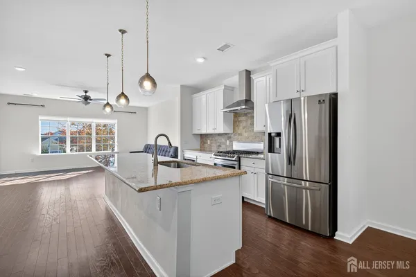 a kitchen with stainless steel appliances granite countertop a refrigerator a stove oven a sink dishwasher and white cabinets with wooden floor