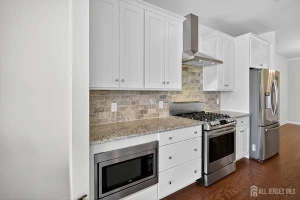 a large kitchen with stainless steel appliances kitchen island a large counter top and a wooden floors