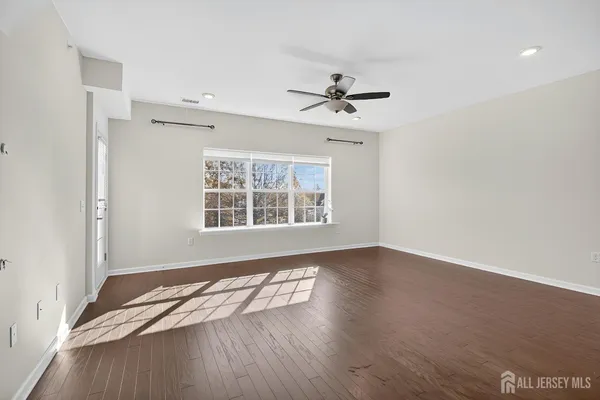 a view of empty room with wooden floor and fan