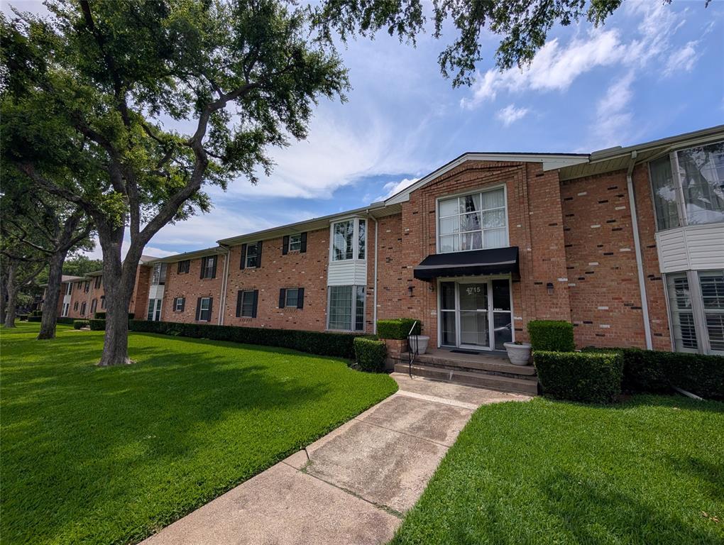 4715 Skillman Street, Unit A Dallas, TX 75206 - Photo 2 of 28 Brick exterior building featuring a prominent entry with a black awning, flanked by established trees and manicured lawns