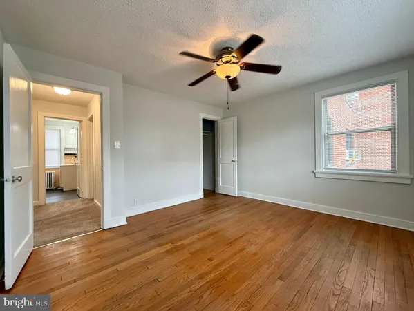 a view of empty room with wooden floor and fan