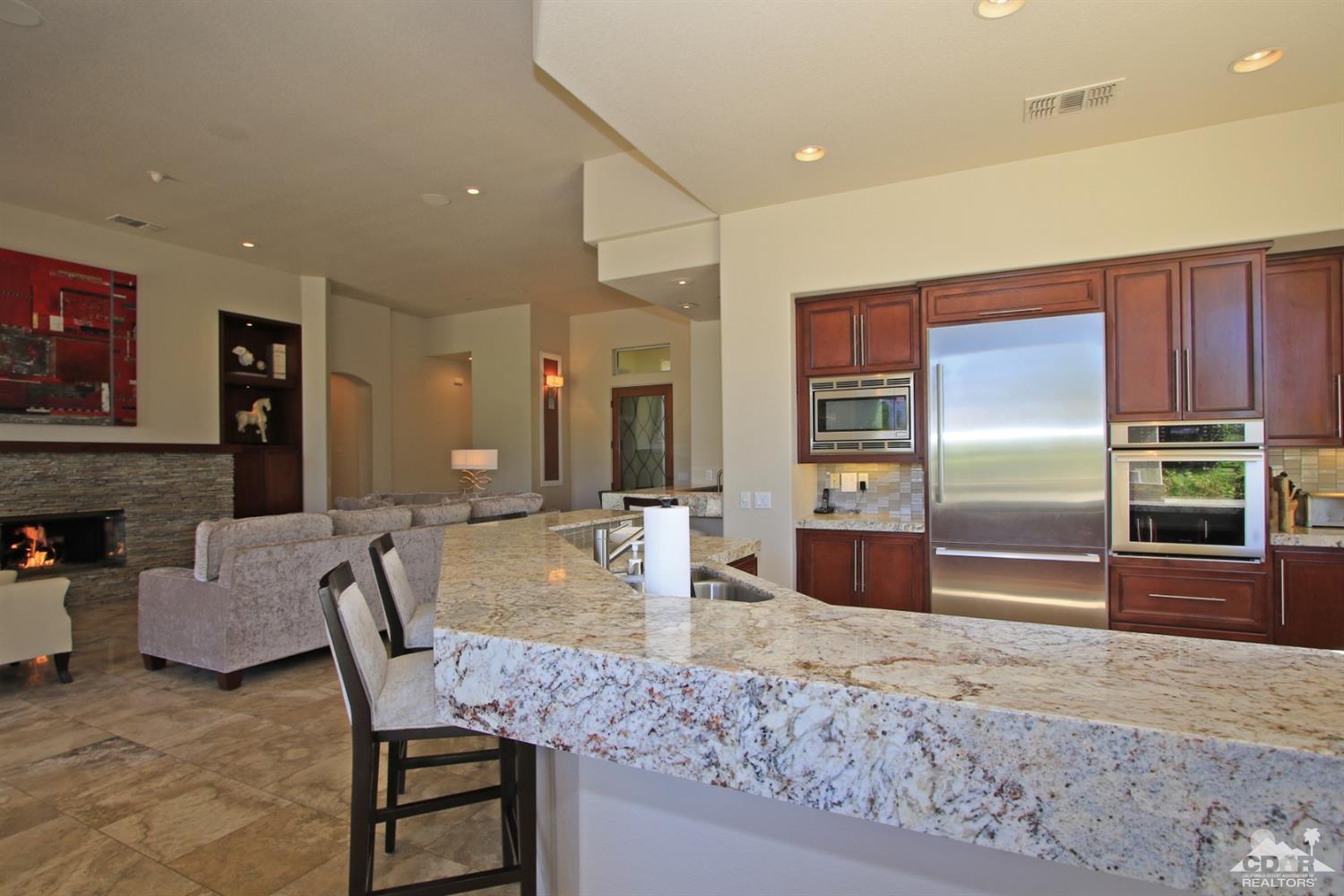 204 Loch Lomond Road Rancho Mirage, CA 92270 - Photo 12 of 45 a kitchen with stainless steel appliances granite countertop a dining table chairs and a refrigerator