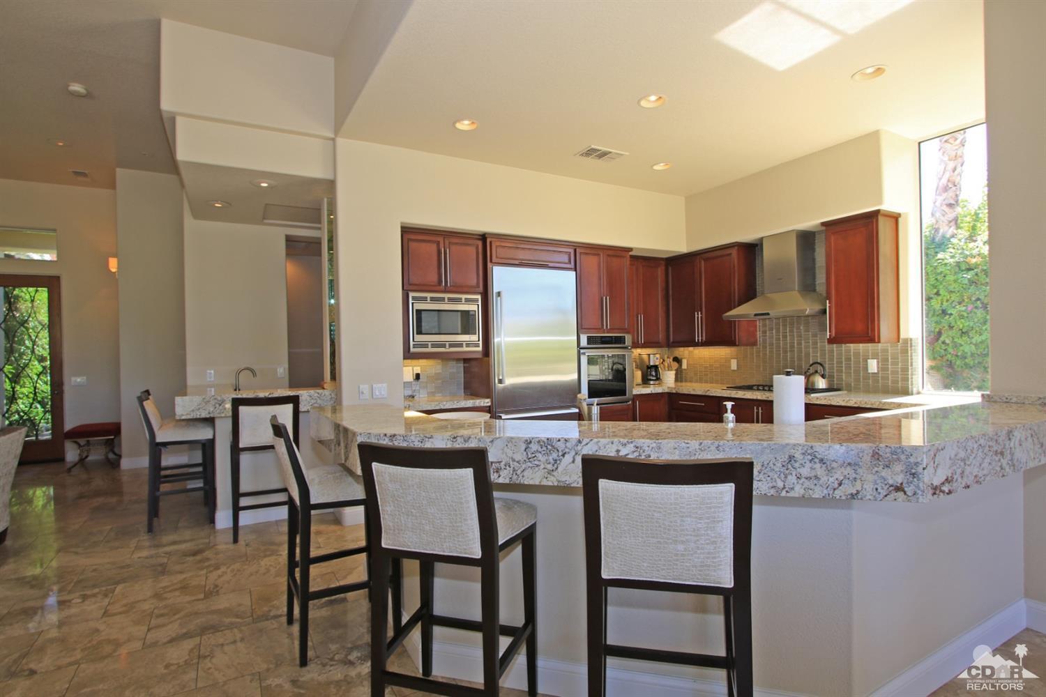 204 Loch Lomond Road Rancho Mirage, CA 92270 - Photo 13 of 45 a kitchen with granite countertop a table chairs microwave and cabinets