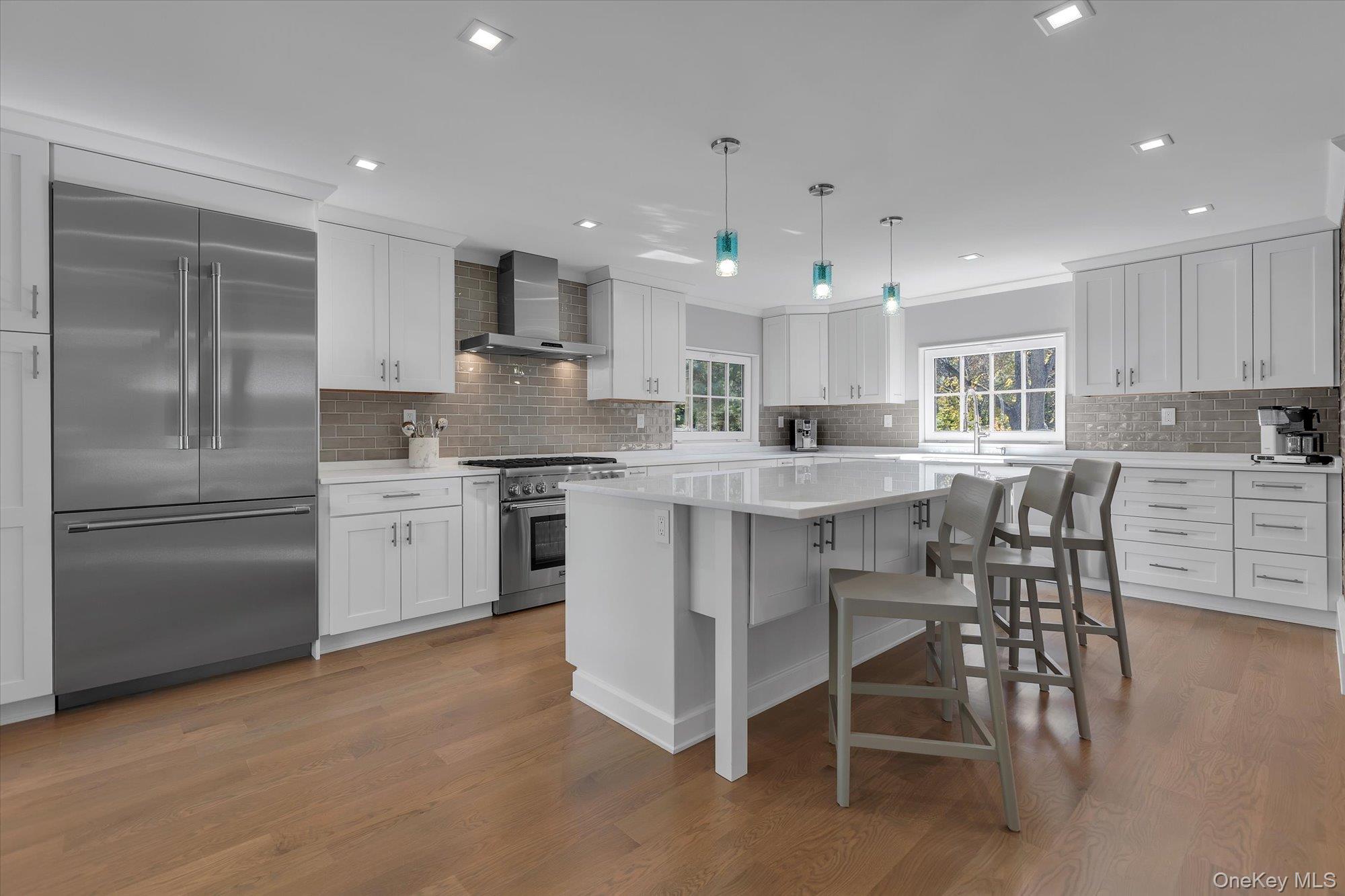 22 Fort Salonga Road Centerport, NY 11721 - Photo 12 of 42 Kitchen with high end appliances, a breakfast bar, exposed brick. range hood, decorative light fixtures, and white cabinetry