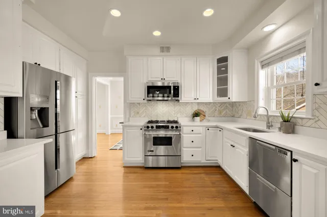 a kitchen with granite countertop white cabinets and stainless steel appliances