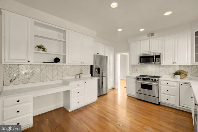 a kitchen with stainless steel appliances a sink cabinets and wooden floor