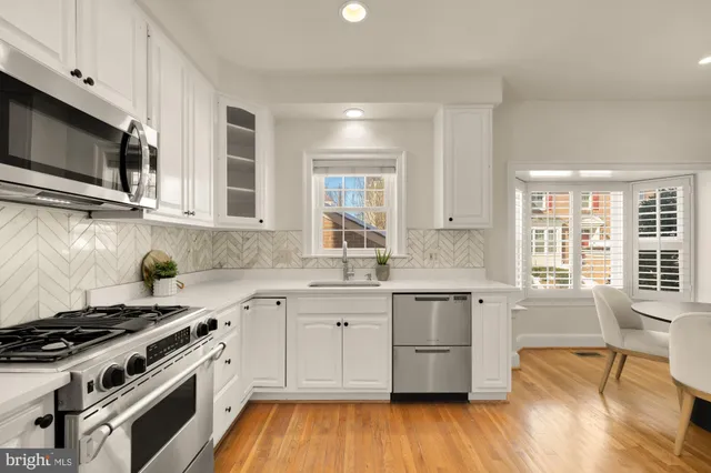a kitchen with cabinets stainless steel appliances a sink and a window