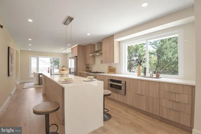 a large kitchen with kitchen island a large window a sink and cabinets
