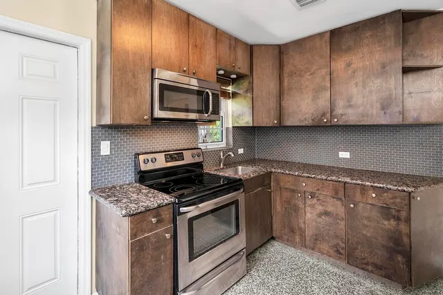 a kitchen with stainless steel appliances granite countertop a stove a sink and a microwave