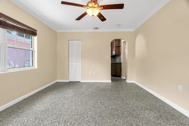 a view of an empty room with chandelier fan and a window