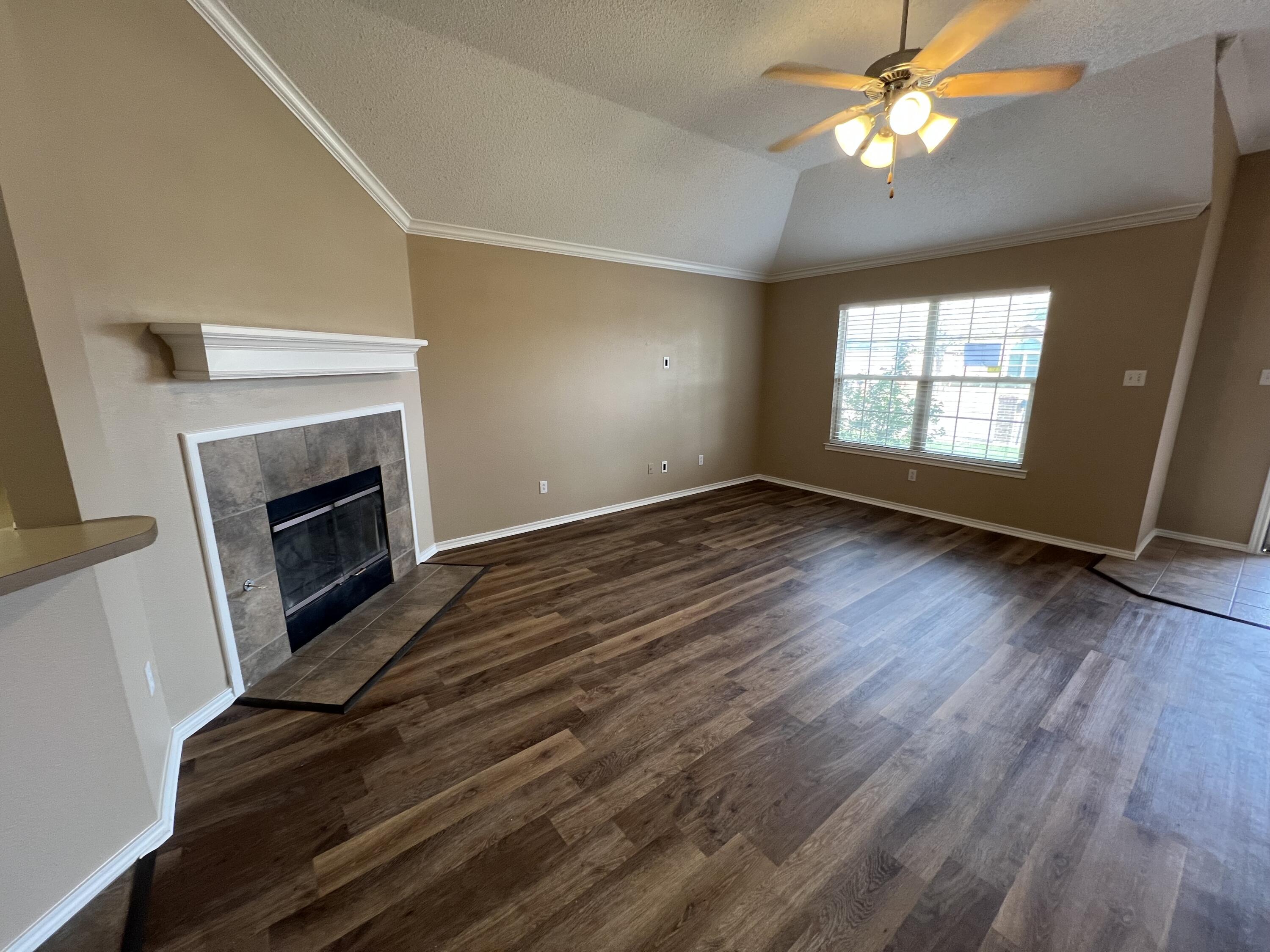 6505 8th Street Lubbock, TX 79416 - Photo 3 of 12 an empty room with wooden floor fireplace and windows