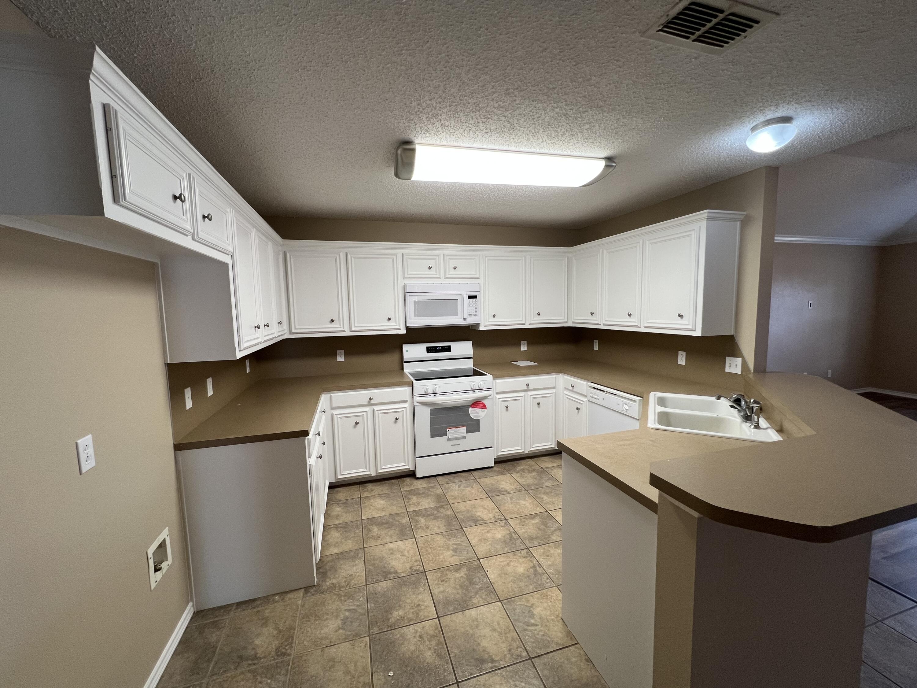 6505 8th Street Lubbock, TX 79416 - Photo 4 of 12 a kitchen with a sink a stove a refrigerator and cabinets
