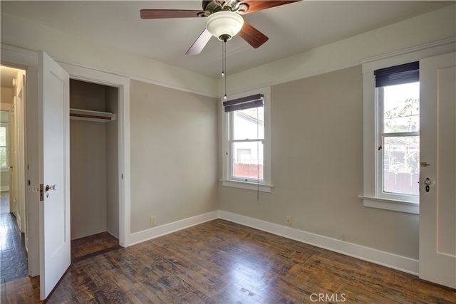 a view of empty room with wooden floor and fan