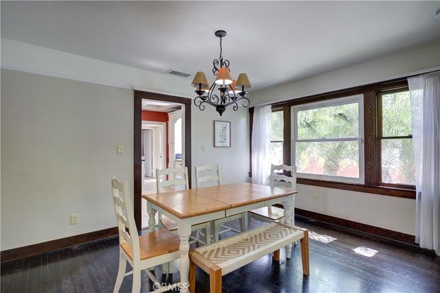 a dining room with wooden floor a chandelier a wooden table and chairs