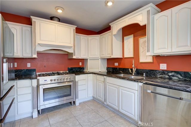 a kitchen with granite countertop a stove sink and cabinets