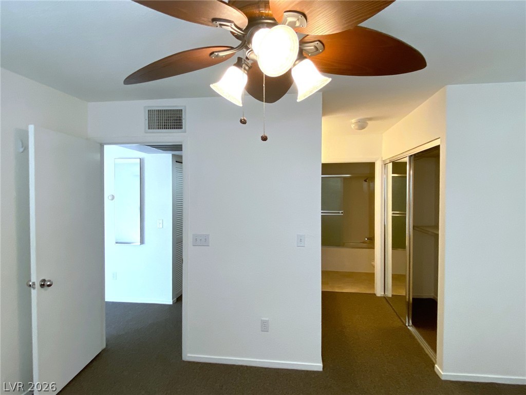 8070 West Russell Road, Unit 2105 Las Vegas, NV 89113 - Photo 5 of 10 A comfortable bedroom features a ceiling fan, soft carpeting, and convenient access to a private bathroom and closet.