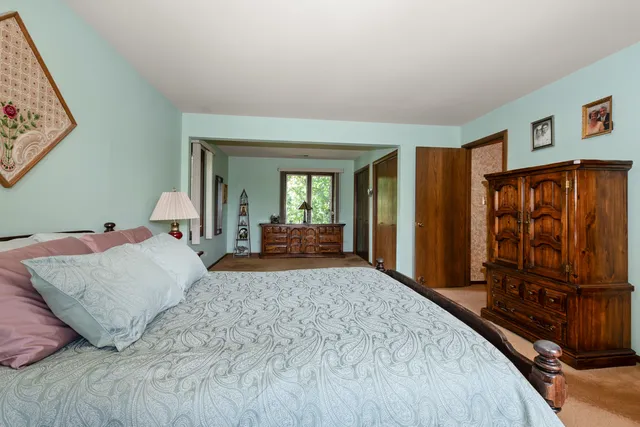a bedroom with a large bed and dresser with mirror