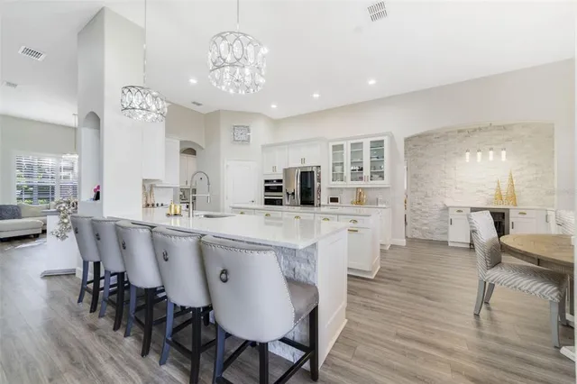 a large kitchen with cabinets a sink dishwasher a dining table and chairs with wooden floor