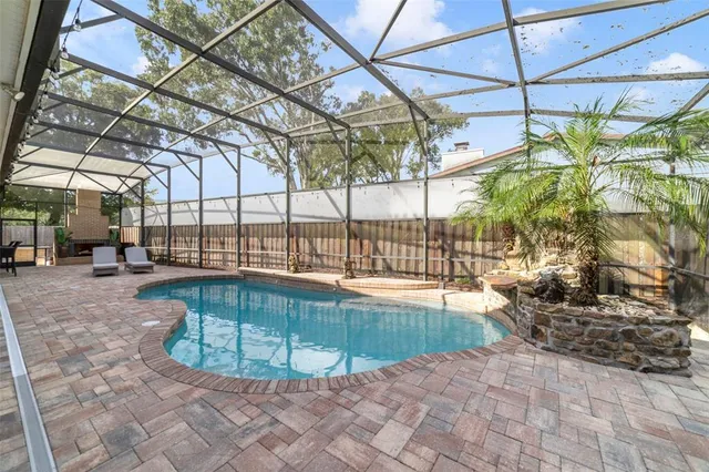 a view of a swimming pool with a patio and a backyard