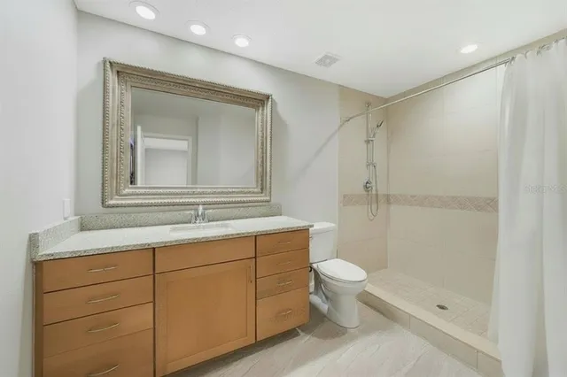 a bathroom with a granite countertop sink toilet and shower