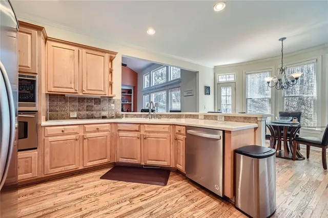 a kitchen with stainless steel appliances granite countertop a stove top oven a sink dishwasher a dining table and chairs with wooden floor