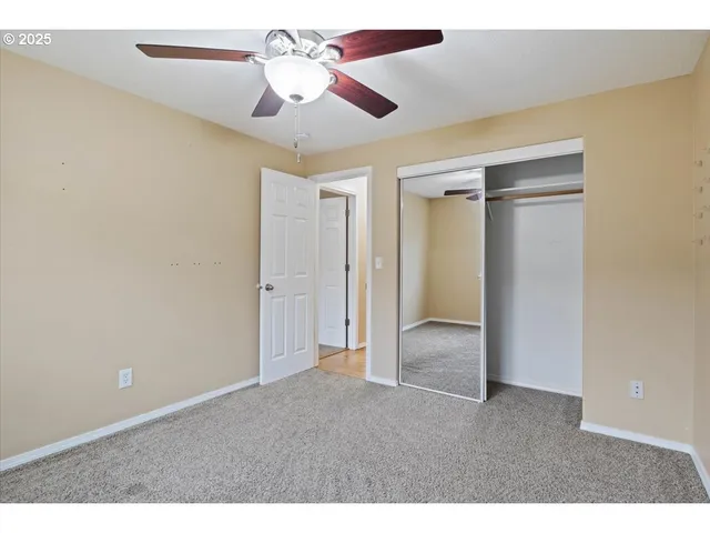 an empty room with closet and a chandelier fan