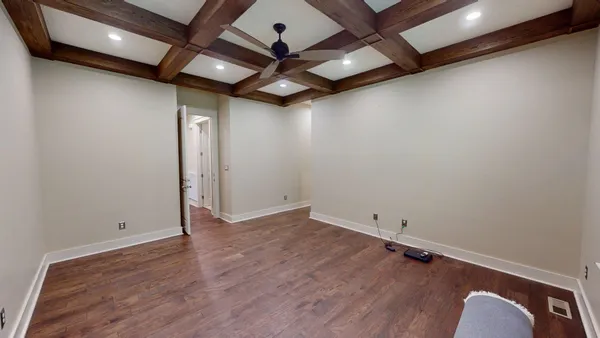 an empty room with wooden floor and a ceiling fan