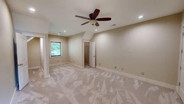an empty room with window and ceiling fan