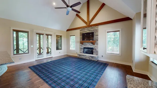 an empty room with wooden floor fireplace and windows