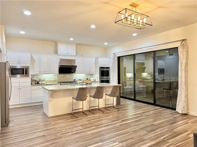 a view of a kitchen with kitchen island a sink stainless steel appliances and cabinets