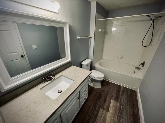 a bathroom with a sink a toilet a mirror and shower