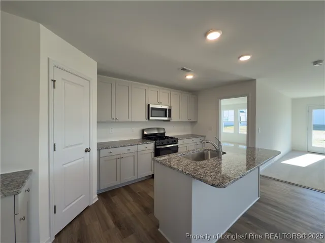 a kitchen with kitchen island granite countertop a sink and refrigerator