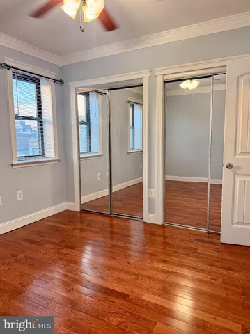 an empty room with wooden floor closet and windows