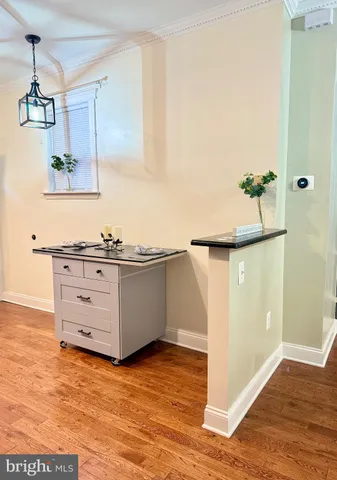 a room with kitchen island a chandelier and wooden floor