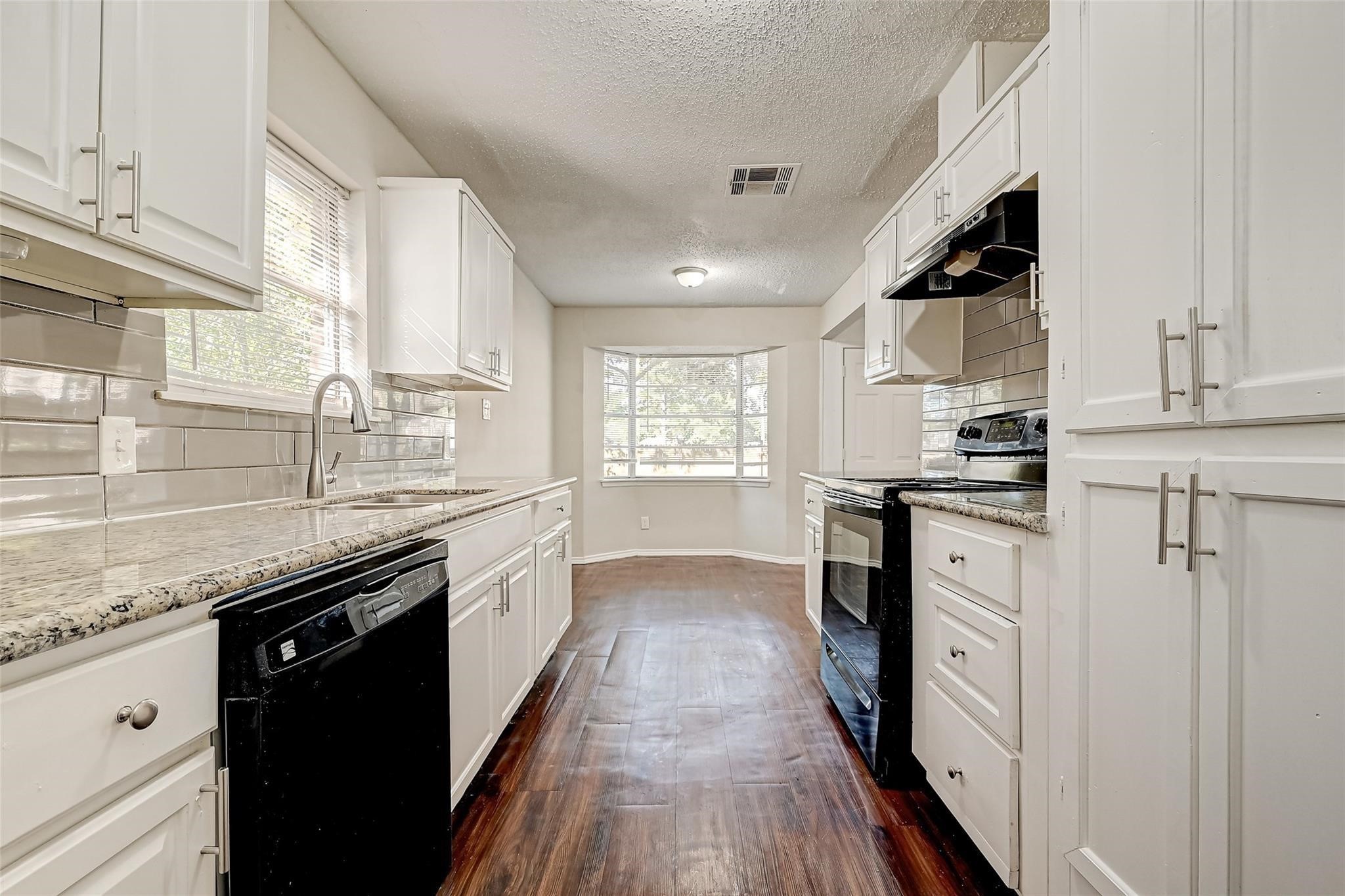 22318 Meadowgate Drive Spring, TX 77373 - Photo 6 of 8 a kitchen with granite countertop kitchen island wooden floors stainless steel appliances